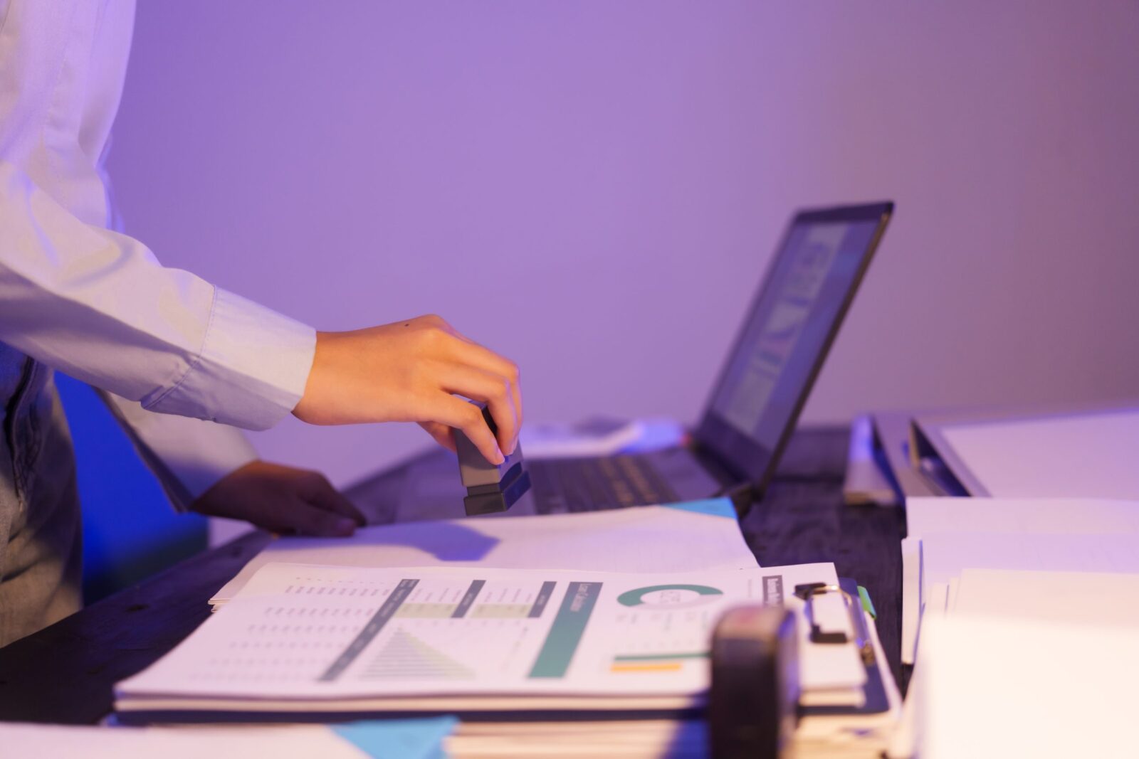 An Asian woman is working overtime at her desk in the office,busy viewing documents her notebook